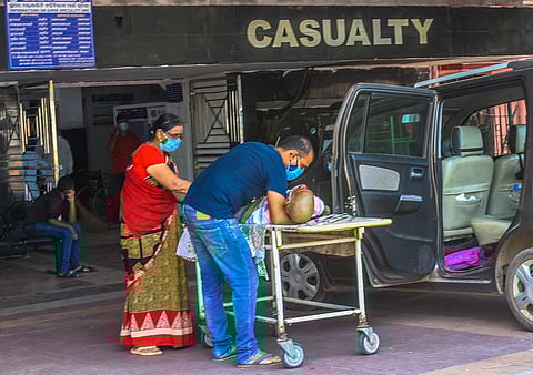 Relatives shifting an elderly person on to a stretcher outside the casualty ward of a hospital in Bhubaneswar. (Photo | Biswanath Swain, EPS)