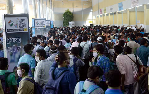 Polling officials wait to collect EVMs and other polling materials on the eve of the 8th phase of the Bengal election, at Netaji Indoor Stadium in Kolkata on Wednesday. (Photo | ANI)