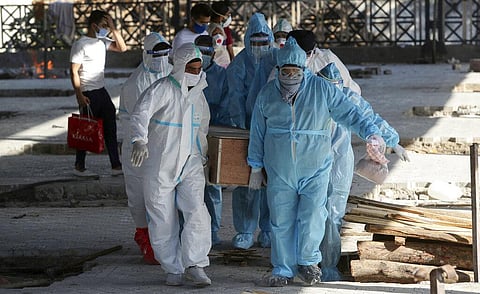 Health workers and relatives carry the body of a COVID-19 victim for cremation in Jammu. (Photo | AP)