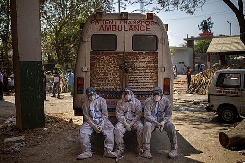 Exhausted workers, who bring dead bodies for cremation, sit on the rear step of an ambulance inside a crematorium, in New Delhi. (Photo | AP)