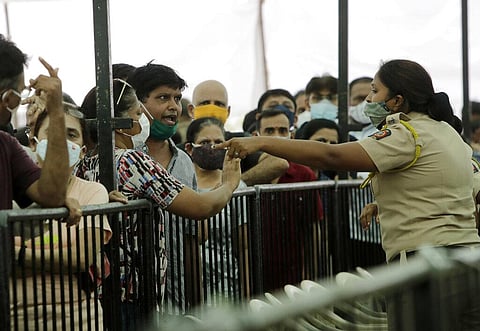 A man argues with a policewoman as he waits with others to receive COVID-19 vaccine outside a vaccination centre in Mumbai. (Photo | AP)