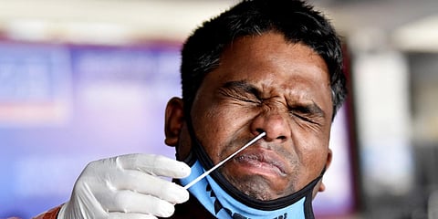 A health worker collects a swab sample of a man for the COVID-19 test at New Delhi railway station. (File photo| ANI)