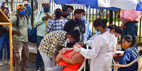 A medic conducts COVID-19 testing of a tourist at Gateway of India as others wait for their turn. (Photo | PTI)
