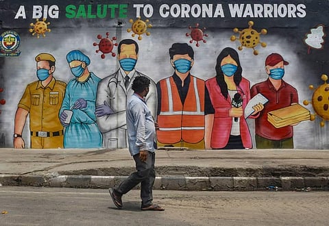 A man walks past a mural that reads 'A Big Salute To Corona Warriors' during ongoing COVID-19 lockdown in New Delhi . (Photo | PTI)