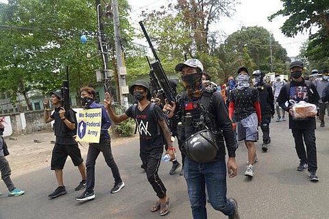 Anti-coup protesters march with homemade air rifles as one of them holds sign showing support for a civilian-formed federal army during a protest march in Yangon. (Photo | AP)
