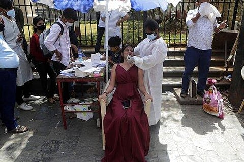 A health worker takes a nasal swab sample to test for COVID-19 near the landmark Gateway of India in Mumbai. (Photo | AP)
