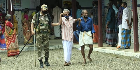 A CISF person helping an elder voter while he returning after castibg his vote at Holy Family Girls High school in Kainakari, Alappuzha. (Photo I Arun Angela, EPS)