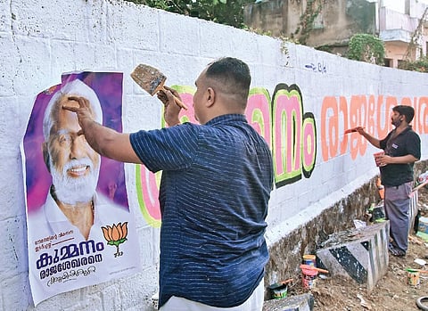 File photo of BJP workers painting the wall and stick posters of BJP candidate from Nemom Kummanam Rajasekharan, at Jagathy in Thiruvananthapuram on Sunday | B P Deepu