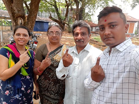 Non-Malayali voters show the ink on their fingers outside a polling station.