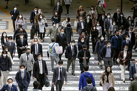 People wearing face masks to help curb the spread of the coronavirus walk in front of Osaka train station in Japan. (Photo | AP)