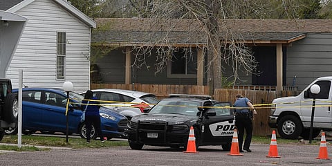 A police officer goes to help a person who was in a different mobile home to be able to get to her car from behind the crime tape in Colorado Springs. (Photo| AP)
