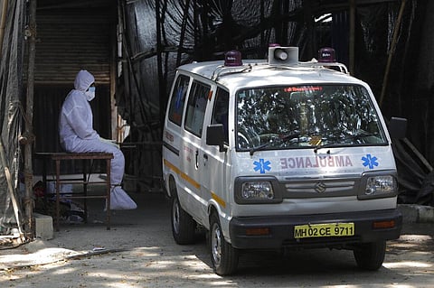 A health worker in personal protective equipment sits beside an ambulance as he takes a break outside a field hospital. (Representational Photo | AP)