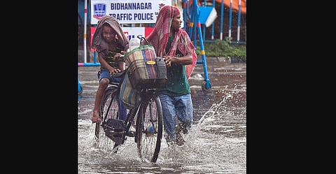 People wade through a water logged road, after heavy rain in Kolkata, Tuesday, May 11, 2021. (Photo | PTI)