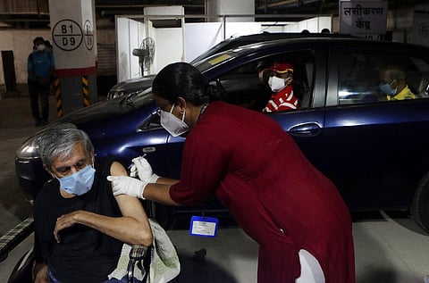 A man receives a vaccine for COVID-19 in his wheelchair at a drive-in vaccination centre in Mumbai. (Photo | AP)