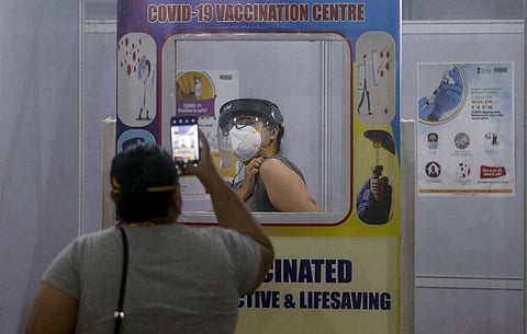 A woman gets herself photographed after getting vaccinated at a selfie point erected to create awareness on COVID-19 vaccination in Mumbai. (Photo | AP)