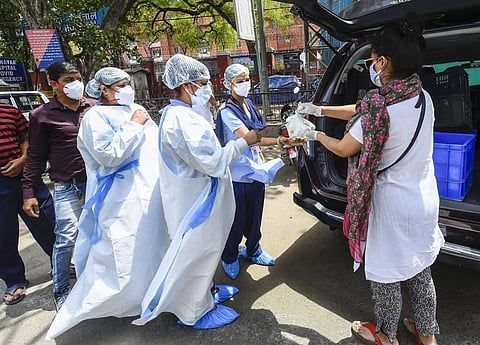 Health workers collect food being distributed by a volunteer outside LNJP Hospital in New Delhi, Wednesday, May 12, 2021. (Photo | PTI)