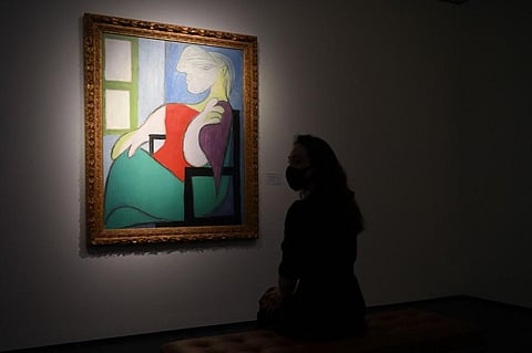 A gallery worker poses alongside an artwork titled 'Femme assise près d'une fenêtre (Marie-Thérèse)' by Pablo Picasso during a photocall at Christie’s auction house in London. (Photo | AFP)