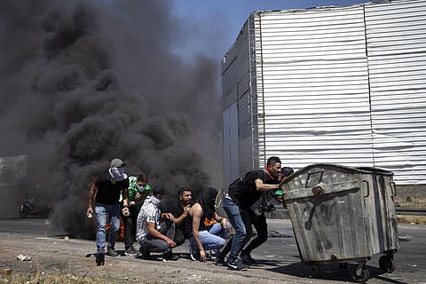 Palestinian demonstrators take cover during clashes with Israeli forces at the Hawara checkpoint, south of the West Bank city of Nablus, Friday, May 14, 2021. (Photo | AP)