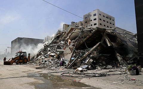 Workers clear the rubble of a building that was destroyed by an Israeli airstrike that housed The Associated Press, broadcaster Al-Jazeera and other media outlets, in Gaza City. (Photo | AP)