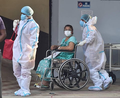 Health workers help a patient during her discharge after she recovered from the COVID-19, at a state government run COVID-19 hospital in Kolkata. (Photo | PTI)