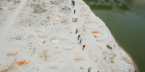 Relatives of COVID19 victim, carry the body covered with saffron clothes at a cremation ground in Prayagraj. (Photo| ANI)