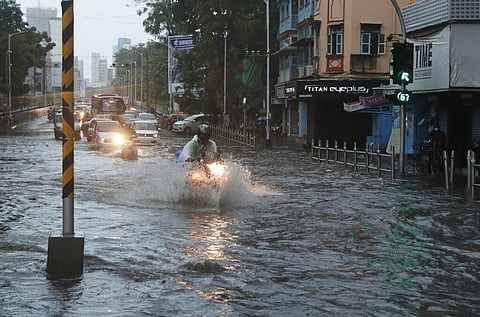 Commuters wade through a waterlogged street during a heavy rain in Mumbai. (Photo | AP)
