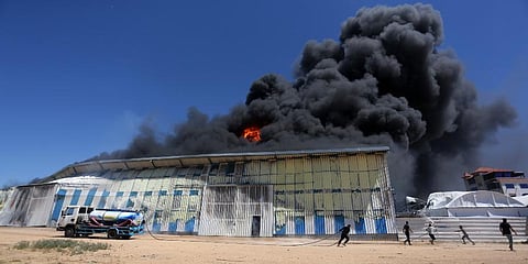 Palestinians use a water tanker to try to extinguish a fire at a paint factory after it was hit by an Israeli airstrike, in Rafah, Gaza Strip. (Photo | AP)