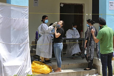 A health worker takes a nasal swab sample of a woman to test for COVID-19 in Jammu. (Photo | AP)
