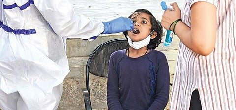 A young girl gives her swab samples for a Covid test at a Primary Health Centre in Bengaluru on Monday | VINOD KUMAR T