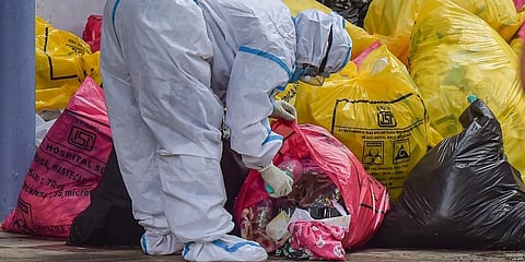 A medical worker sorts medical waste before sending for disposal, at a COVID-19 hospital. (Photo | PTI)