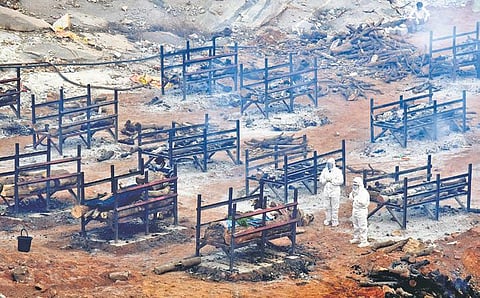 People in PPE kits perform the last rites of their loved ones who died from Covid-19, amidst multiple pyres at Giddenahalli, in Bengaluru on Saturday | VINOD KUMAR T