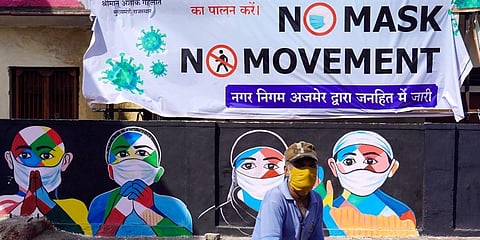 A man cycles past a mural on COVID safety measures, in Ajmer, Friday. (Photo | PTI)