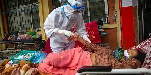 Nepalese paramedics treat a COVID-19 patient outside an emergency ward of a government run hospital in Kathmandu. (Photo | AP)