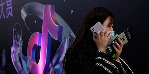 A woman speaks on her phone near the logo for Douyin in Beijing on Wednesday, March 31, 2021. (Photo | AP)