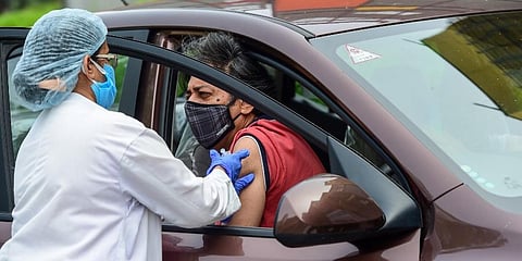 A health worker administers a dose of COVID-19 vaccine to a woman at a drive-through vaccination camp at a mall in Noida, Thursday. (Photo | PTI)