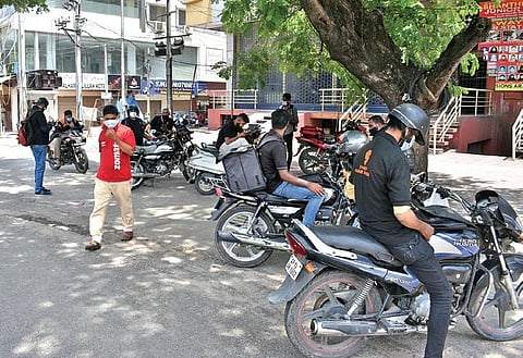 Food delivery agents wait for their turn to collect food packages for customers at a restaurant near Tolichowki in Hyderabad | S Senbagapandiyan