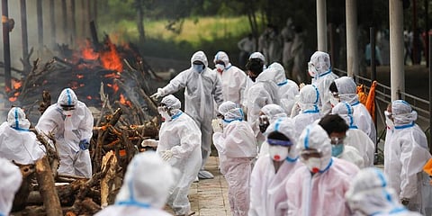 Family members wearng PPE kit perform last rites of a COVID-19 victim in Jammu. (Photo | PTI)