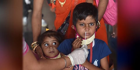 A health worker collects swab sample of a child passenger at a COVID-19 testing counter at New Delhi railway station. (Photo | PTI)