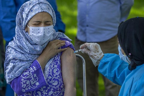 A health worker administers Covishield, Serum Institute of India's version of the AstraZeneca vaccine to a woman as people are inoculated against COVID-19 at a park in Srinagar. (Photo | AP)