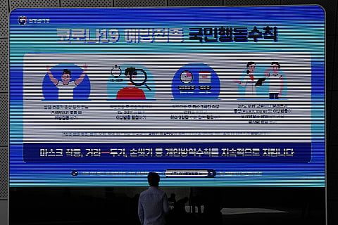 A man wearing a face mask looks at a screen displaying precautions against the coronavirus in Seoul, South Korea. (Photo | AP)