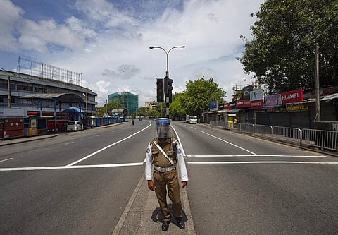 A Sri Lankan policeman stands at an intersection on a deserted street. (Photo | AP)