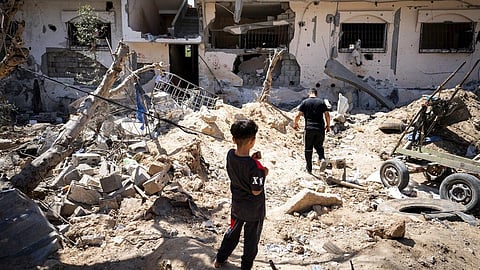 People stand in a clearing strewn with debris from an israeli airstrike during an 11-day war between Gaza's Hamas rulers and Israel.