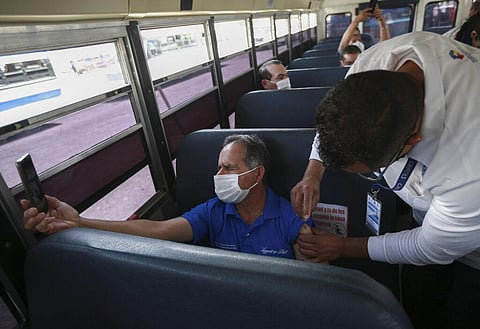 A health worker administers the COVID-19 Pfizer vaccine to maquiladora workers, inside a bus at the parking lot of the Benito Juarez Olympic Stadium in Ciudad Juarez, Mexico. (Photo | AP)