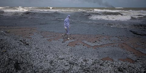 Sri Lankan navy soldiers clad in a protective suit inspects the damage caused to the beach from the debris washed ashore from the burning Singaporean ship. (Photo | AP)