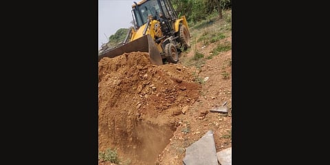 Earthmovers digging a pit in a graveyard in Dharwad to cremate a COVID victim (Photo | Express)