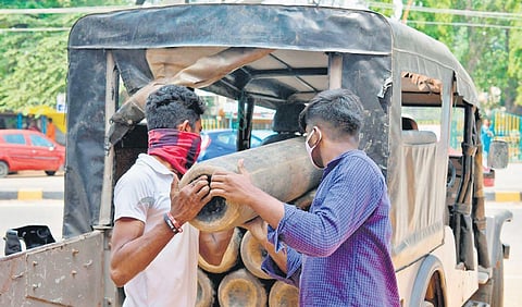 Hospital workers load empty oxygen cylinders on to a vehicle to be transported to a refilling centre in Bengaluru | AFP