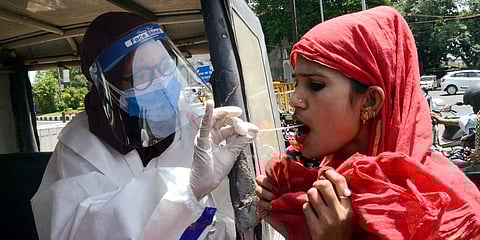 A medic wearing a PPE kit collects a swab sample of a woman for the COVID-19 test. (Photo| ANI)
