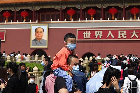 A man and child wearing masks visit Tiananmen Gate near the portrait of Mao Zedong in Beijing. (Photo | AP)