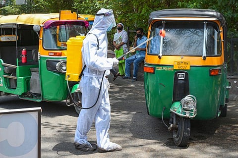 A health worker wearing a PPE kit sanitizes auto-rickshaws in New Delhi. (Representstional Photo | PTI)