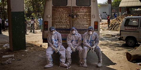 Exhausted workers, who bring dead bodies for cremation, sit on the rear step of an ambulance inside a crematorium, in New Delhi. (File Photo | AP)
